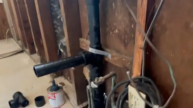 Black drain pipe and fittings inside an open wall frame.