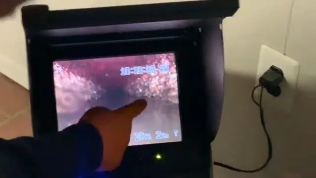 Camera monitor with a hand pointing to a pipe interior on the screen.