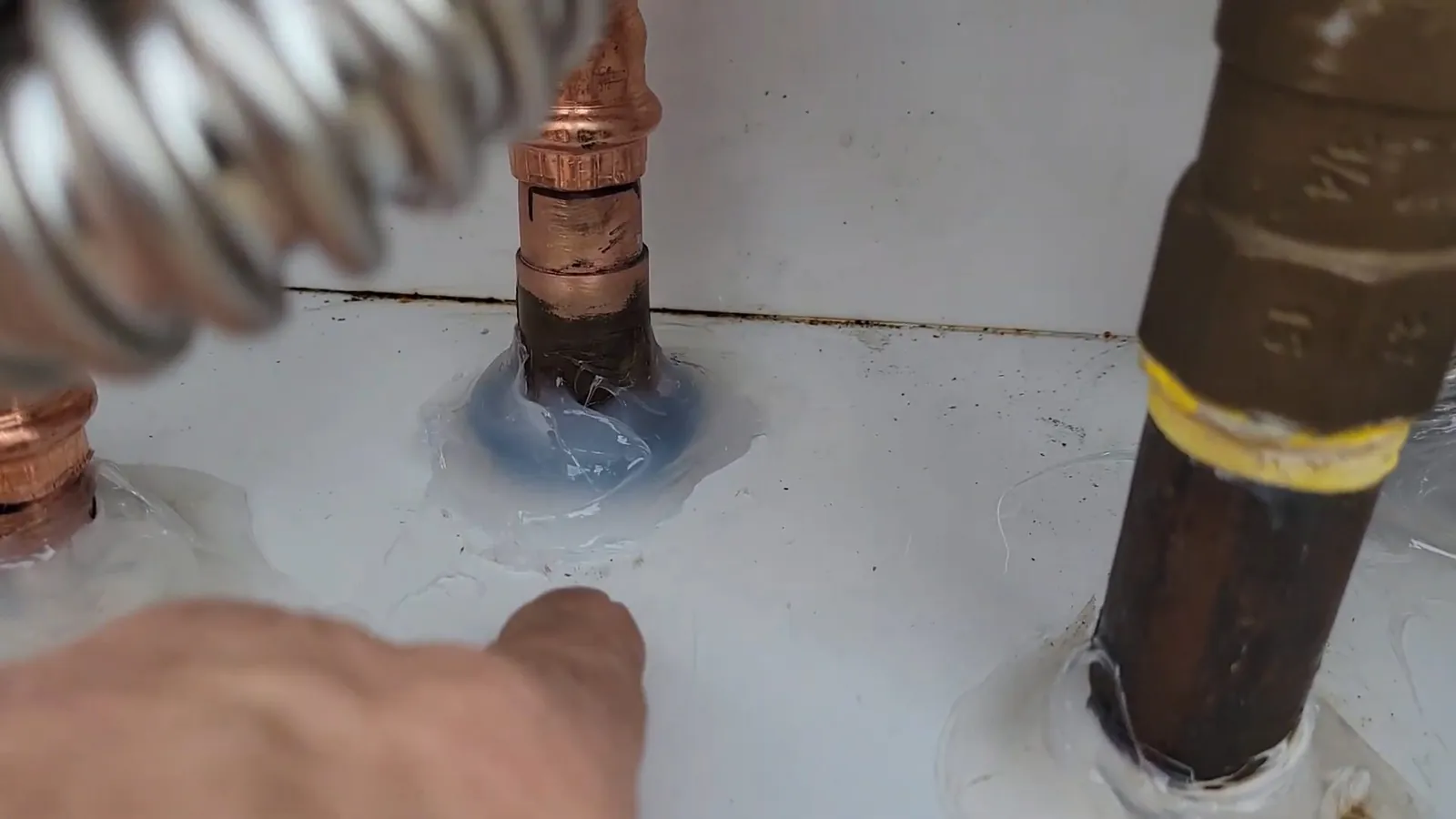 Corrugated stainless gas connector, a copper pipe stub and a brass-wrapped gas line passing through a sealed surface.
