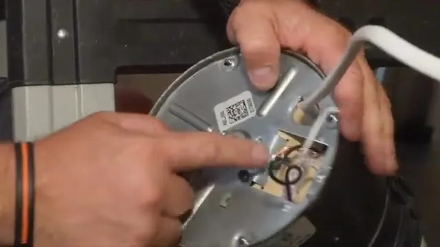 Finger on the bottom plate of a garbage disposal with a hex wrench set into its center socket.