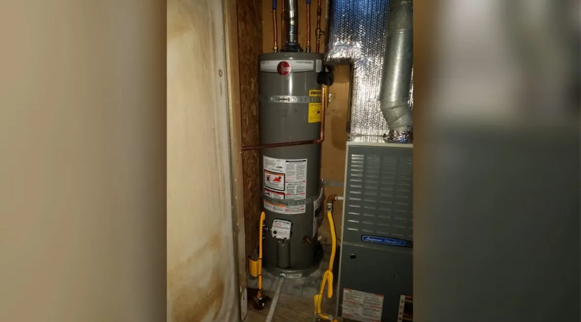 Tank water heater in a narrow utility closet beside a furnace.