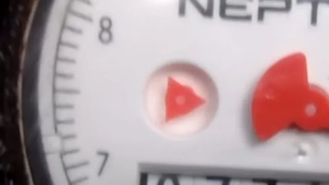 Close-up of a water meter dial with a red triangular flow indicator.