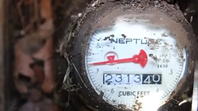 Close-up of a water meter dial with a numbered register and a small flow wheel.